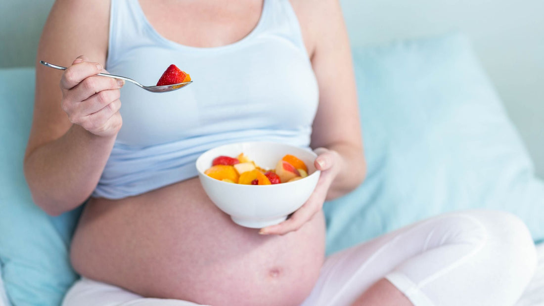 donna incinta che mangia frutta e segue un'alimentazione sana nel primo trimestre di gravidanza